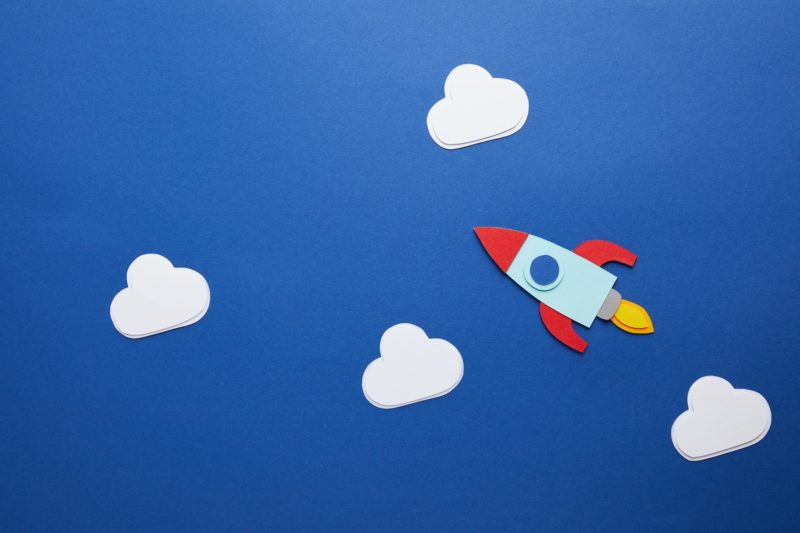 white clouds and rocket on blue background